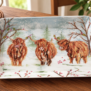 Rectangular ceramic plate featuring a winter scene with three shaggy Highland cows in a snowy forest.