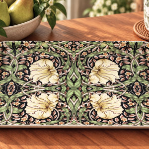 Decorative rectangular ceramic tray with a green-yellow floral pattern on a dark background, on a wooden table beside pears and a mug.